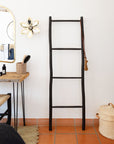 Échelle décorative noire utilisée comme porte-serviettes dans une chambre moderne