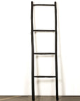 Échelle porte-serviettes en bois noir appuyée contre un mur blanc - utilisation déco