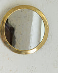 Miroir rond en laiton accroché au mur. Fait main
