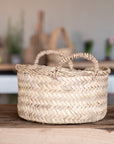 Corbeille en palmier tressé avec anses dans un intérieur bohème