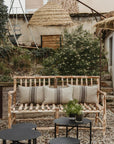 Canapé NAMA en bois brut dans un jardin, entouré de végétation