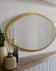 miroir ovale en laiton doré au-dessus d’une console COSYDAR