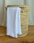 Panier à linge rond en palmier tressé avec serviette blanche, utilisation salle de bain ou chambre