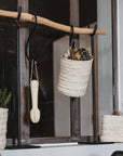 Corbeilles et paniers en fibres naturelles tressées, suspendus sur une tringle en bois, décoration artisanale et naturelle pour la maison
