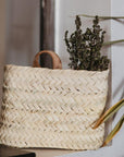 Petit panier mural bohéme tressé en feuille de palmier avec des plantes séchées