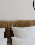 Tête de lit artisanale en bois brut et feuille de palmier tressée. Fait main, matières naturelles.