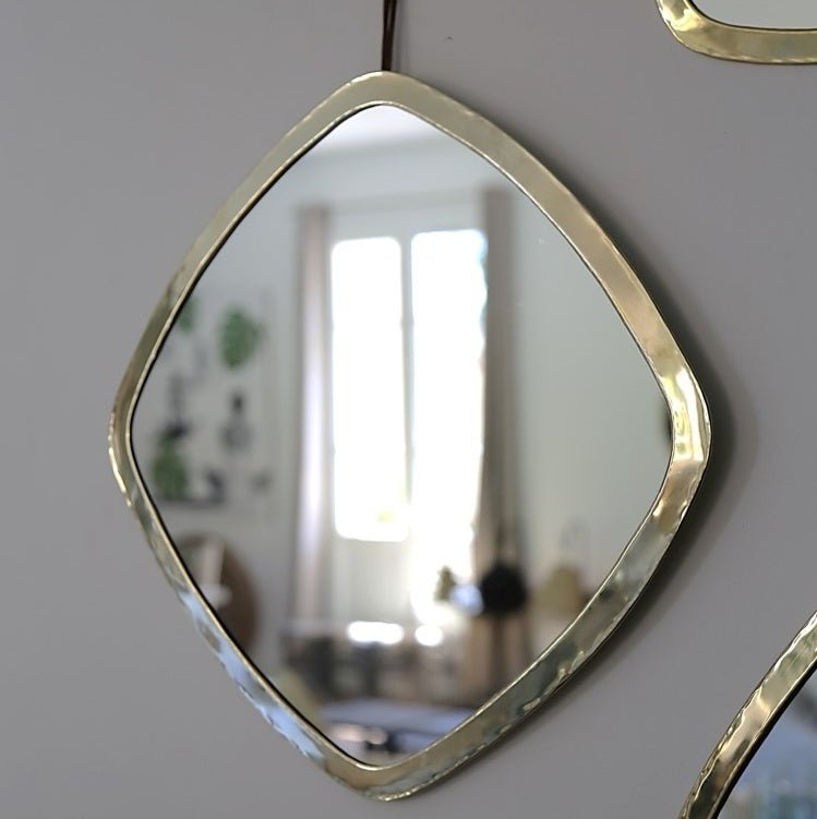 Miroir mural carré doré en laiton accroché à un mur dans un salon