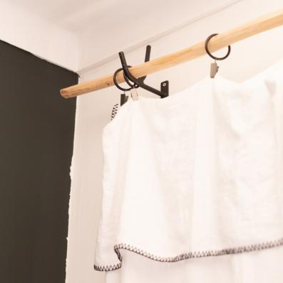 Tringle à rideaux en bois naturel fixé sur un support mural en metal