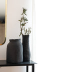 2 GRANDS VASES EN CÉRAMIQUE NOIR POSÉS SUR UNE CONSOLE EN MÉTAL DANS UN SALON