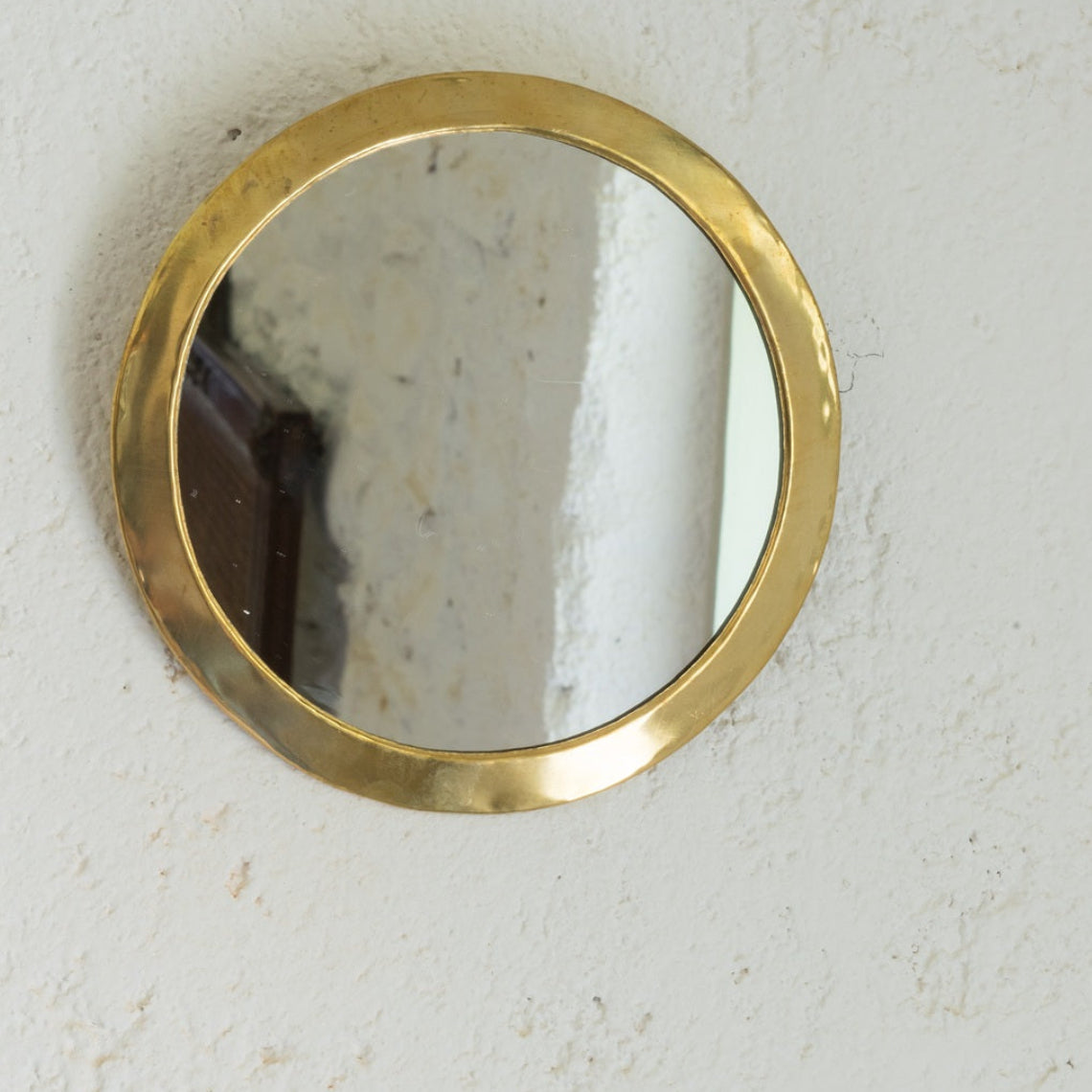 Miroir rond en laiton accroché au mur. Fait main
