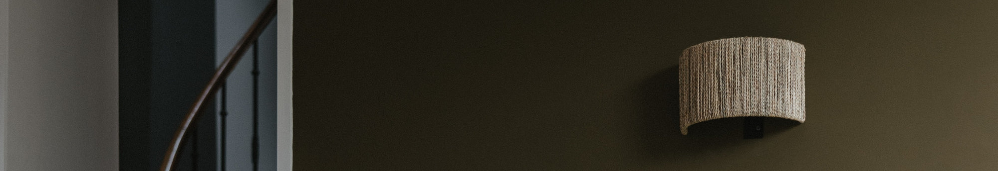 Applique murale tressée en fibre naturelle mise en valuer sur un mur peint en kaki