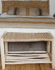 Banc bois naturel tressé placé en bout de lit dans une chambre bohème