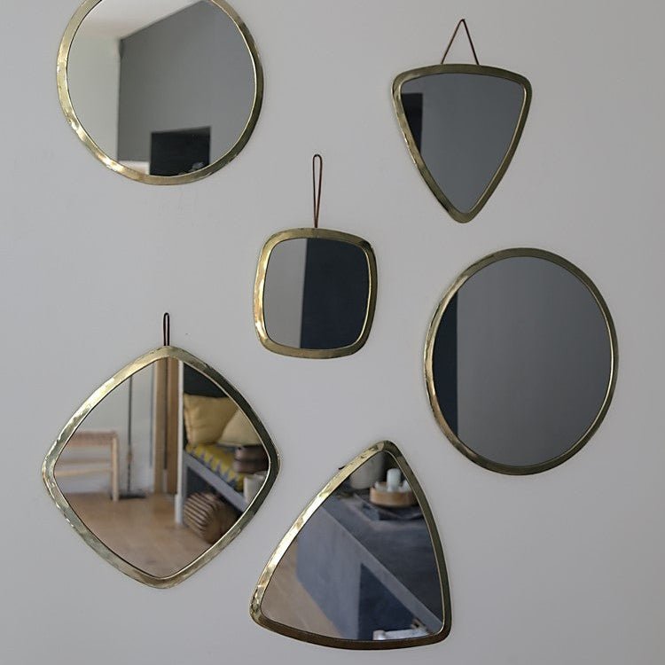 Ensemble de miroirs en laiton doré de formes variées, dont un modèle triangulaire Cosydar, créant une décoration murale originale