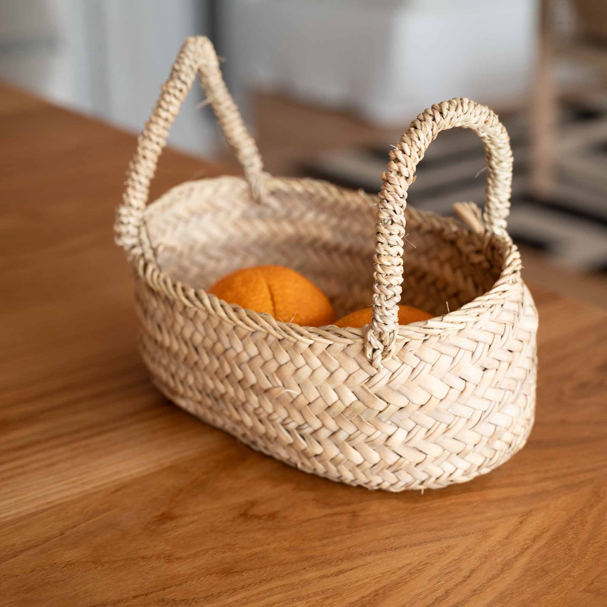 Panier en corde de palmier avec grandes anses tressées avec des oranges sur un plan de travail dans une cuisine - COSYDAR