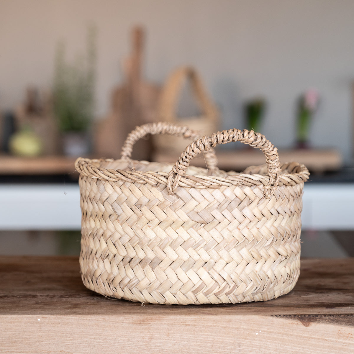 Corbeille en palmier tressé avec anses dans un intérieur bohème