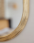Détail du cadre martelé d’un miroir ovale en laiton doré Cosydar, finition brillante et raffinée.