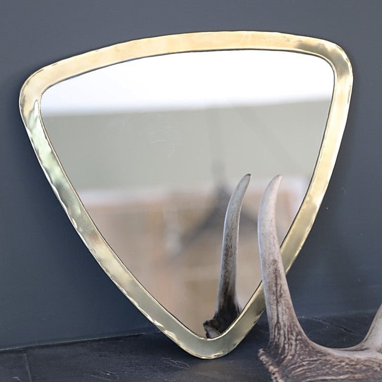 Détail du cadre laiton d’un miroir triangulaire doré Cosydar, finition laiton brillante et forme géométrique élégante.