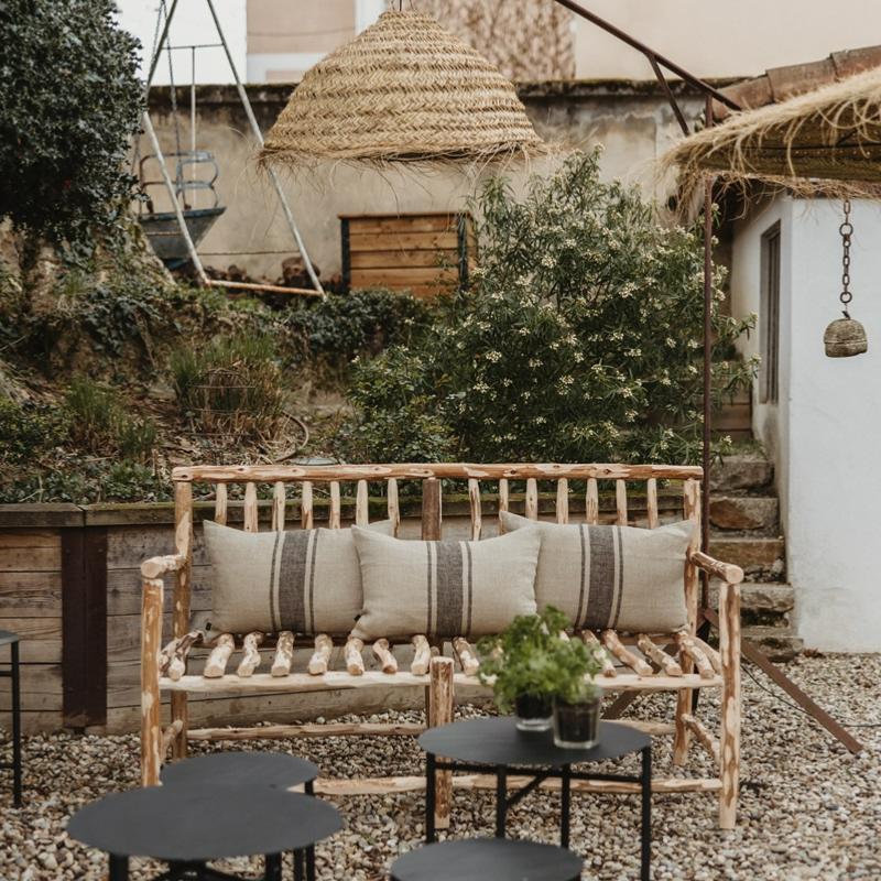 Canapé NAMA en bois brut dans un jardin, entouré de végétation