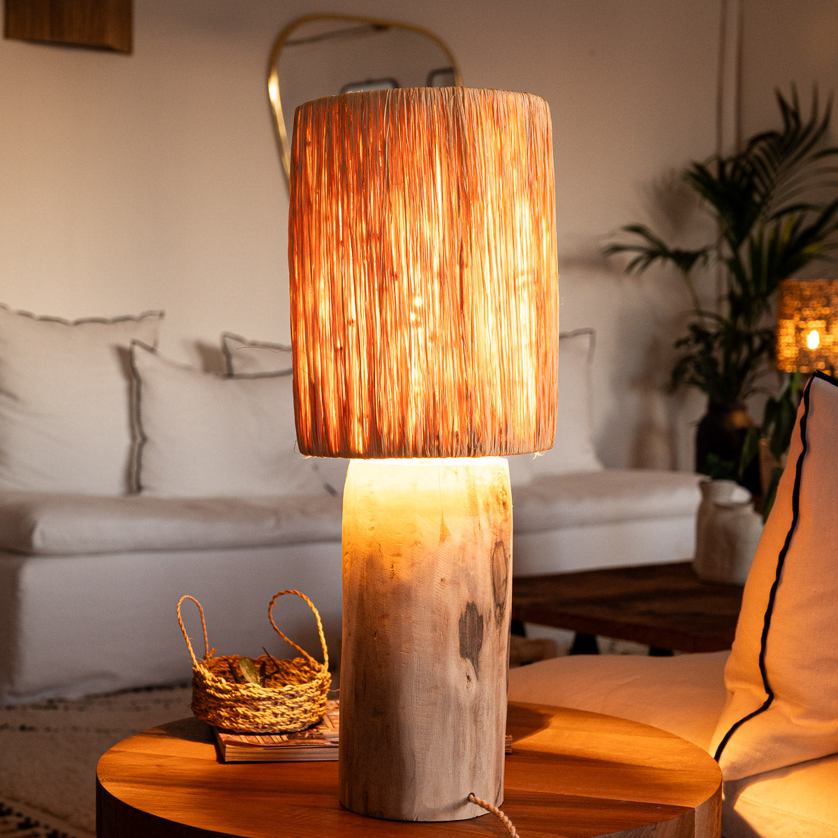 Lampe à poser TANA raphia allumée – lumière douce et tamisée dans un salon bohème – Cosydar