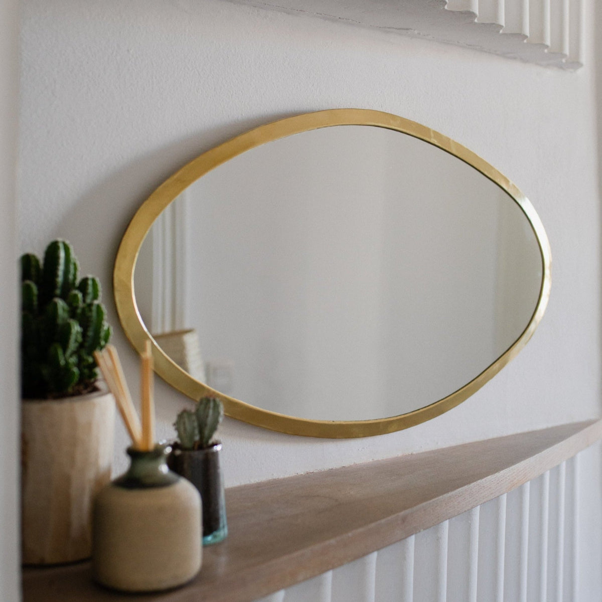 miroir ovale en laiton doré au-dessus d’une console COSYDAR