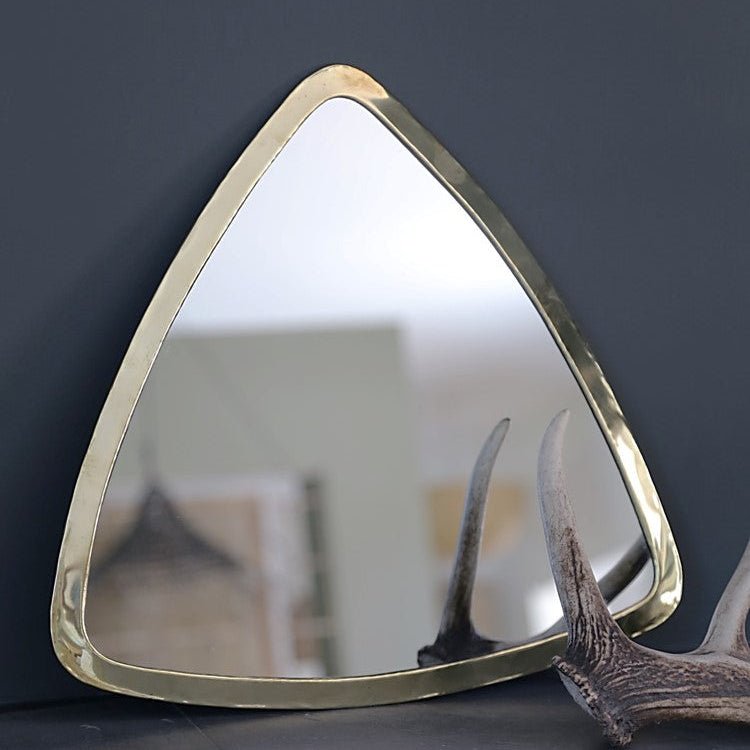 Miroir triangulaire doré Cosydar posé au mur dans une décoration bohème et lumineuse, au-dessus d’un meuble