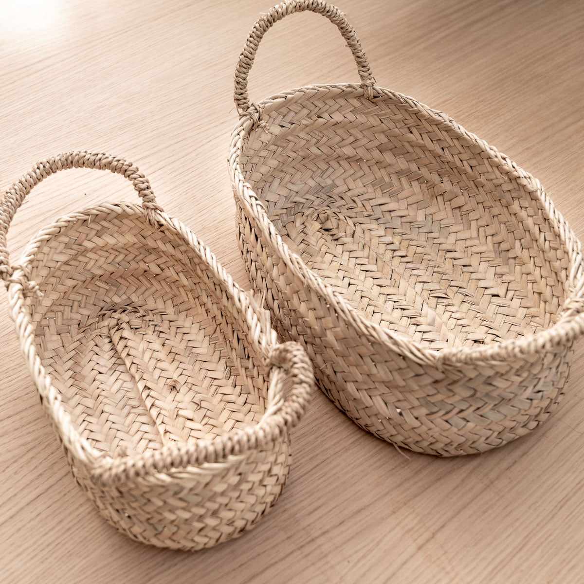 2 paniers de rangement avec anses posés sur une planche en bois