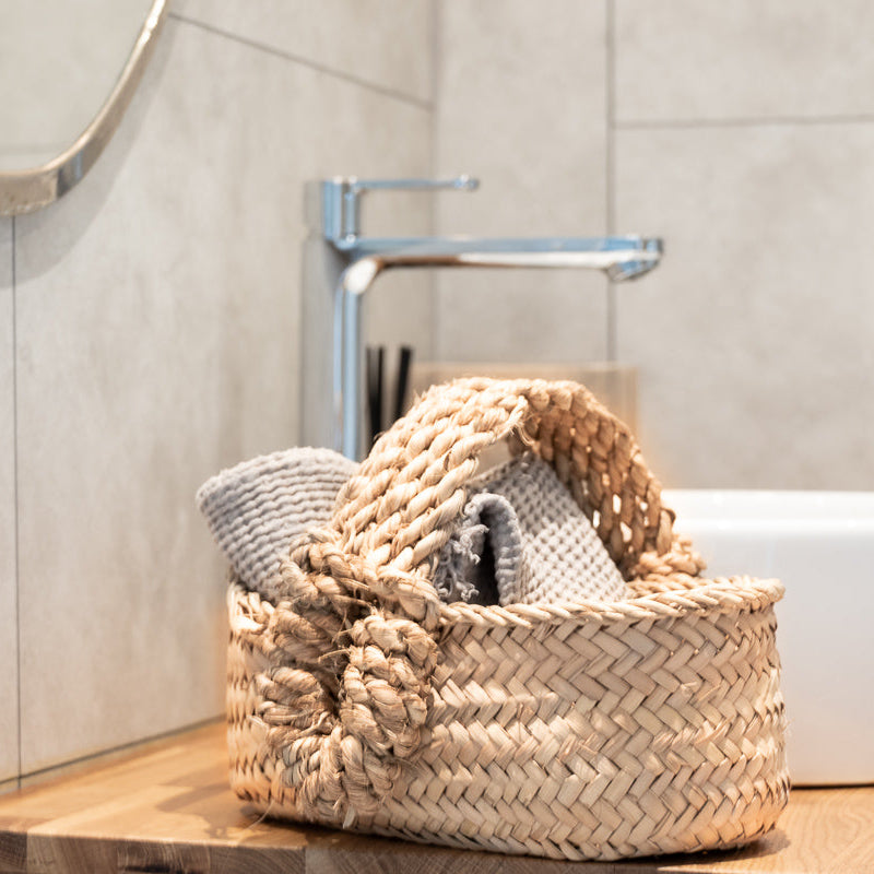 Panier avec anses tressés dans une salle de bain avec petites serviettes