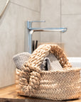Panier avec anses tressés dans une salle de bain avec petites serviettes
