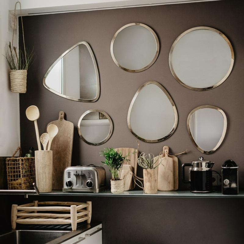Égouttoir en Bois Artisanal dans une cuisine avec un mur de miroirs argentés et autres accessoires de cuisine en bois et en fibre naturelle