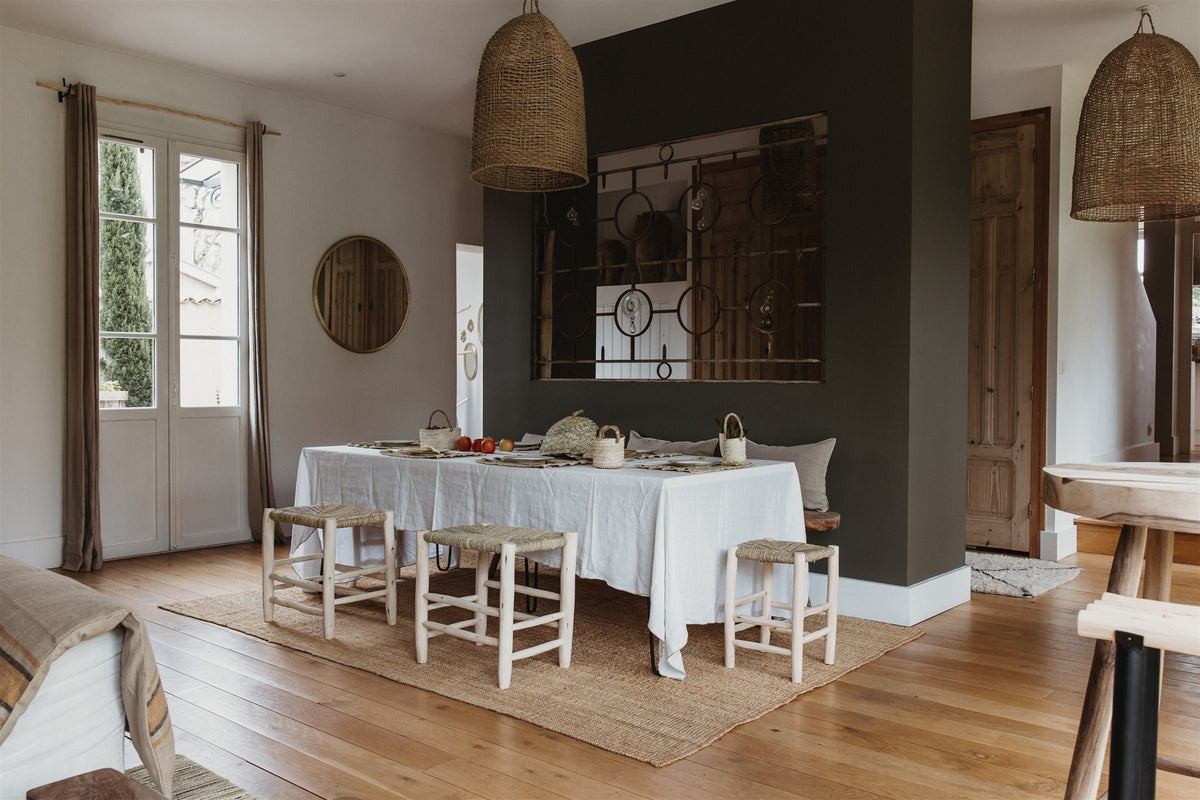 Salle à manger méditerranéenne avec tabourets en bois brut, suspensions en fibres naturelles tressées et miroir rond – Cosydar