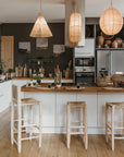 Trois suspensions raphia naturel tressées au-dessus îlot central cuisine bohème et tabourets en bois Cosydar
