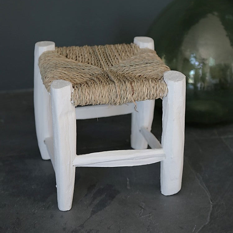 Détail du petit tabouret en bois peint en blanc tressé en fibre naturelle