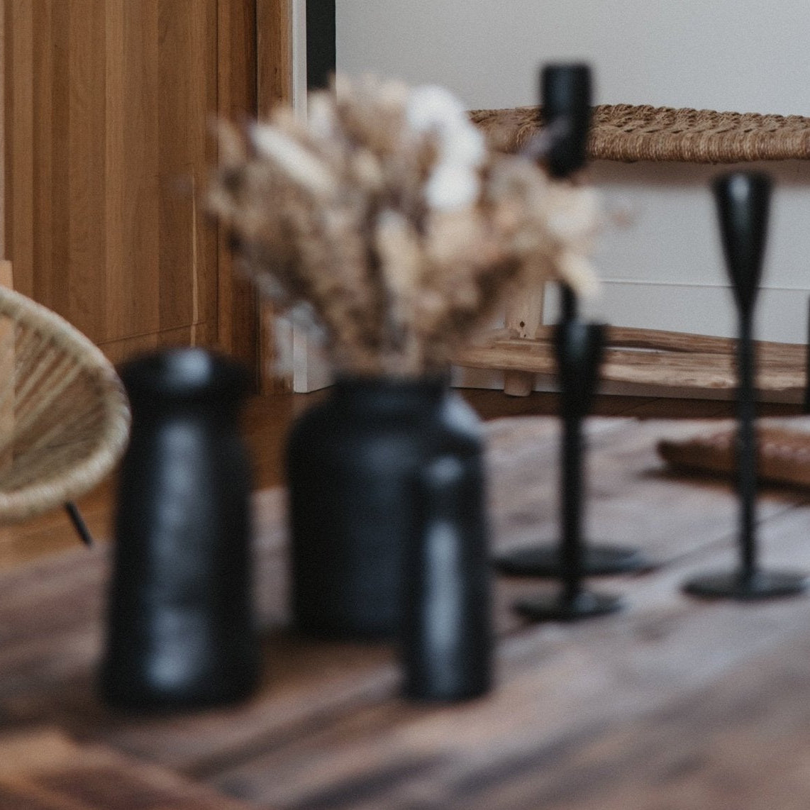 Vases et bougeoires noirs sur une table basse en bois bohéme